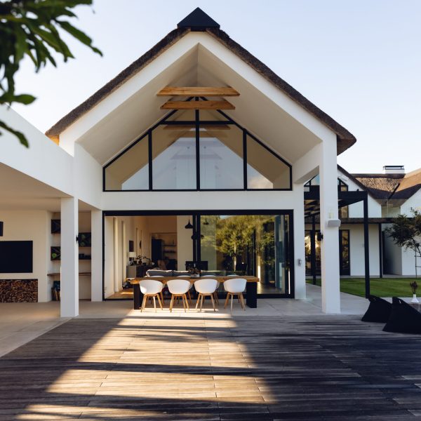 View of luxurious modern house exterior with dining space and garden. Modern architecture and designing concept